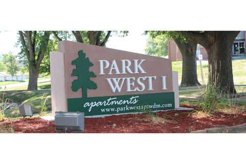 a sign for park west 1 in front of a tree