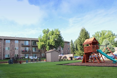 a playground with a tree house in front of an apartment building