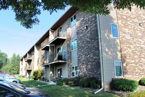 a brick apartment building with balconies and a parking lot