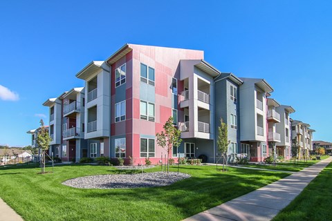 an apartment building with a green lawn and a sidewalk