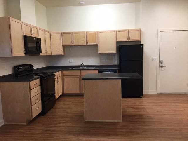 A kitchen with wooden cabinets and black appliances.