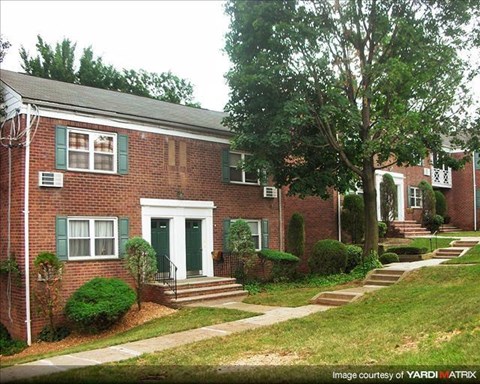 A brick house with green shutters and a white door.