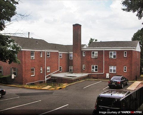 A brick building with a parking lot in front.