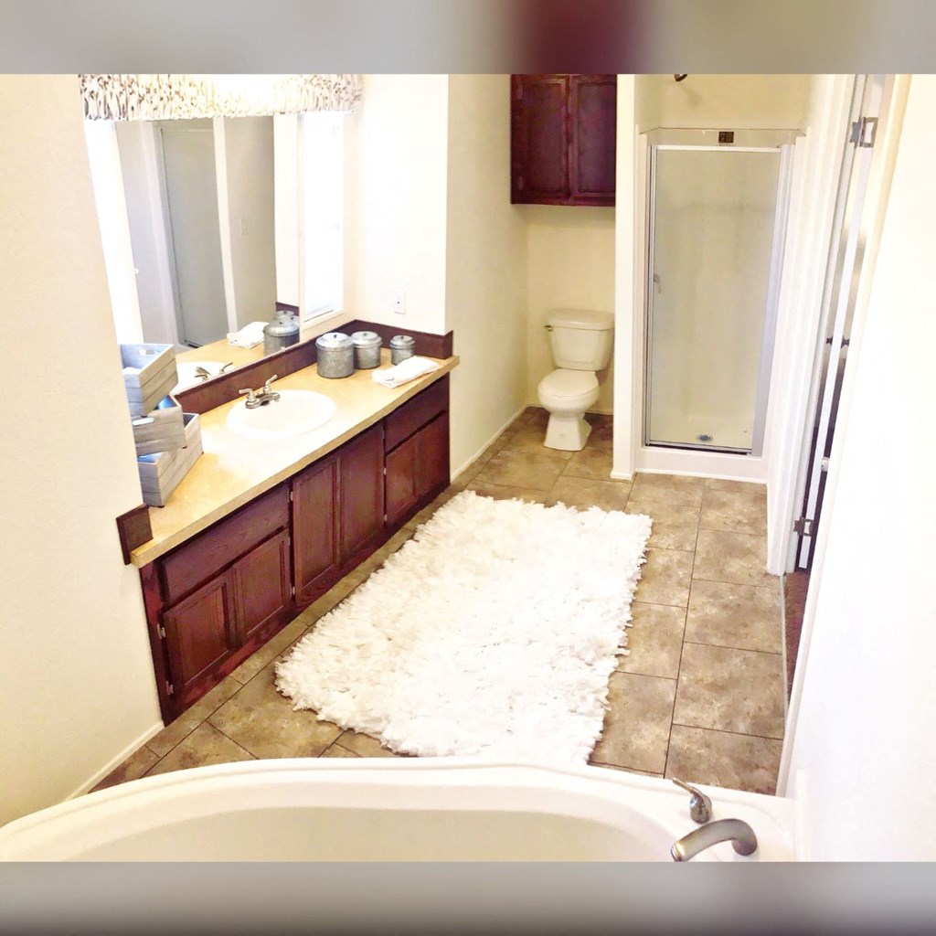 a bathroom with a white rug on the floor and a shower