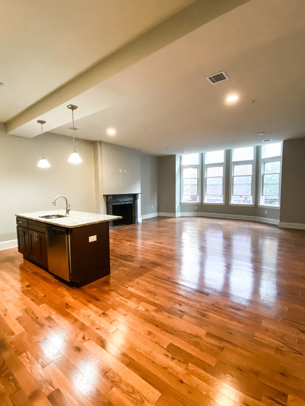 an empty kitchen and living room with wood floors and a fireplace