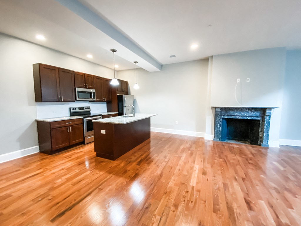 a living room with a fireplace and a kitchen with wooden floors
