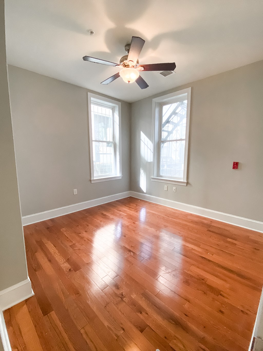 an empty living room with wooden floors and a ceiling fan