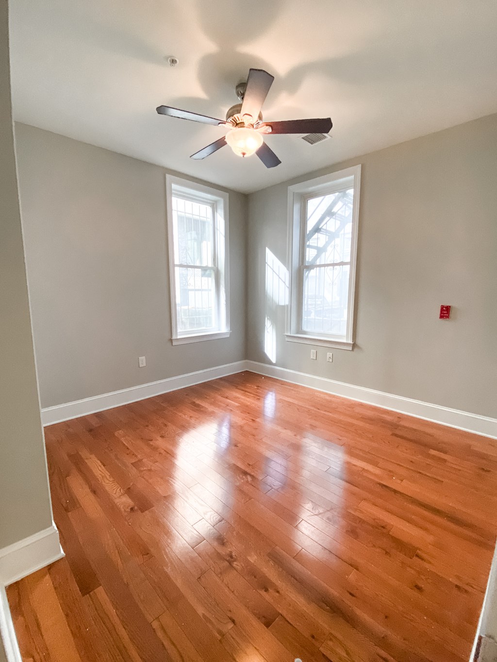 an empty living room with wooden floors and a ceiling fan