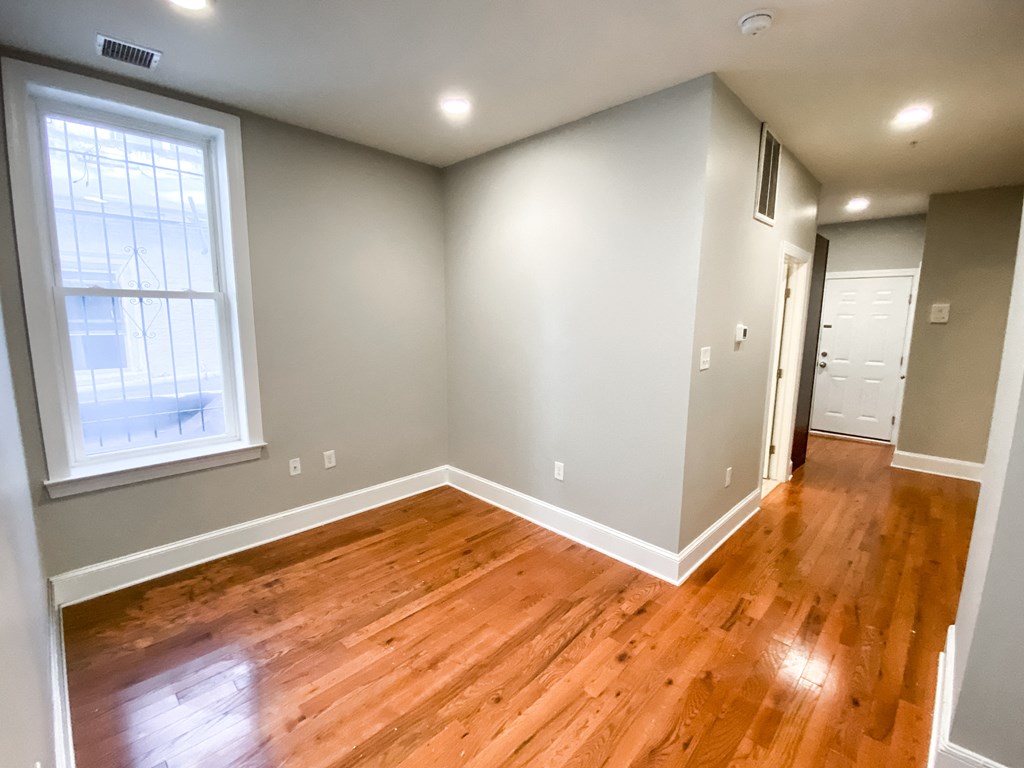 an empty living room with wood floors and a window