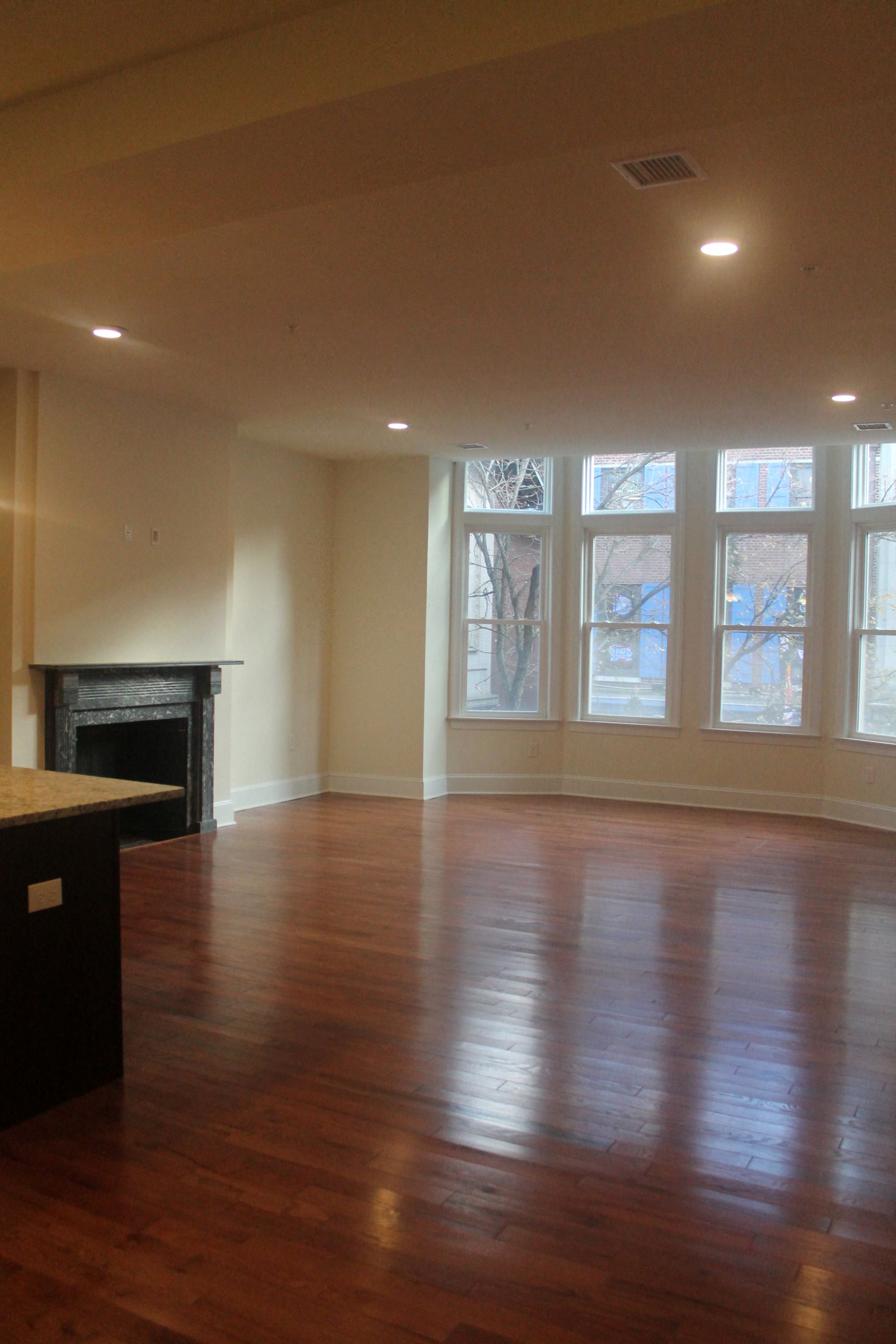 an empty living room with a fireplace and wooden floors