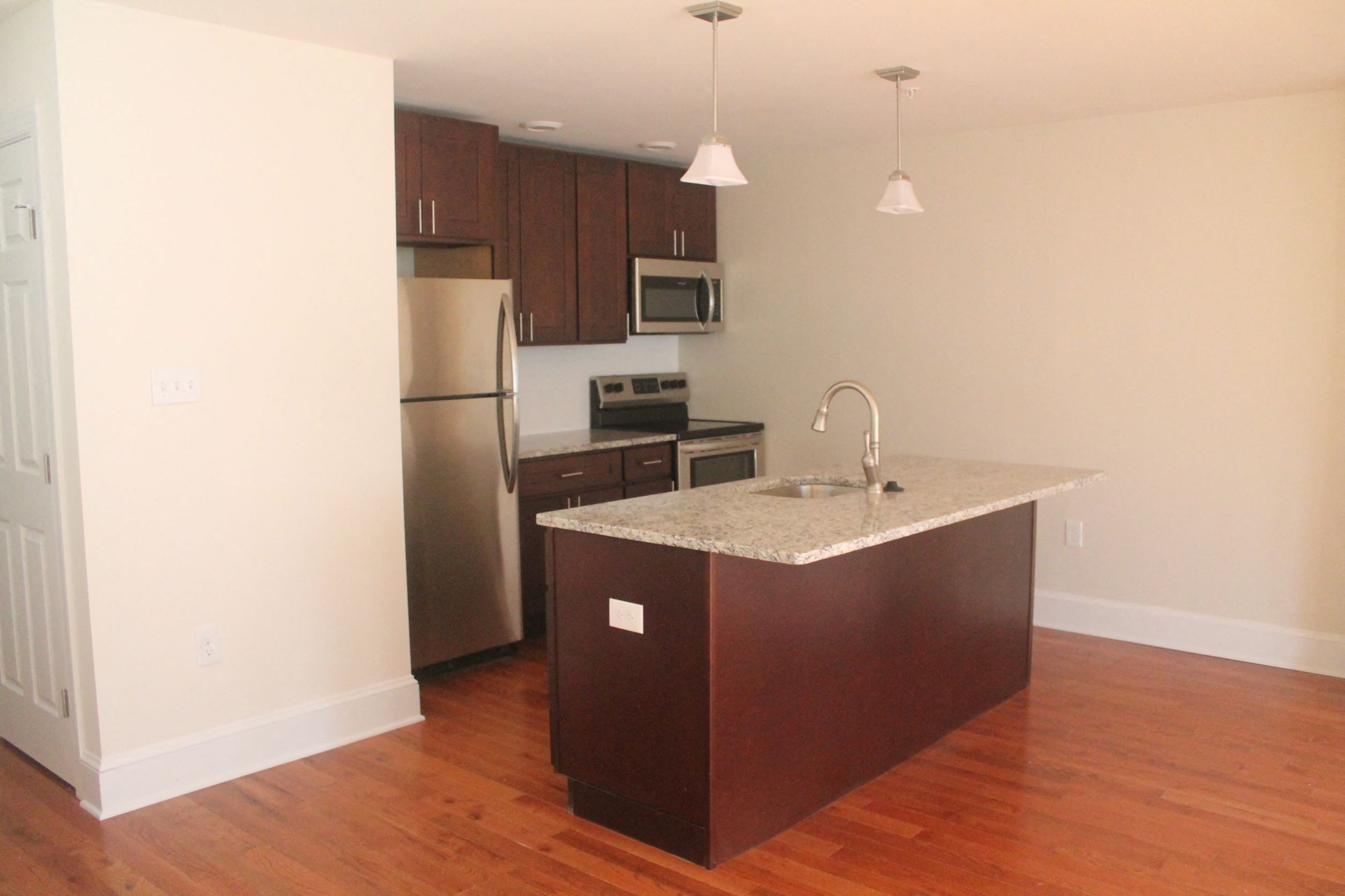 an empty kitchen with an island and stainless steel appliances