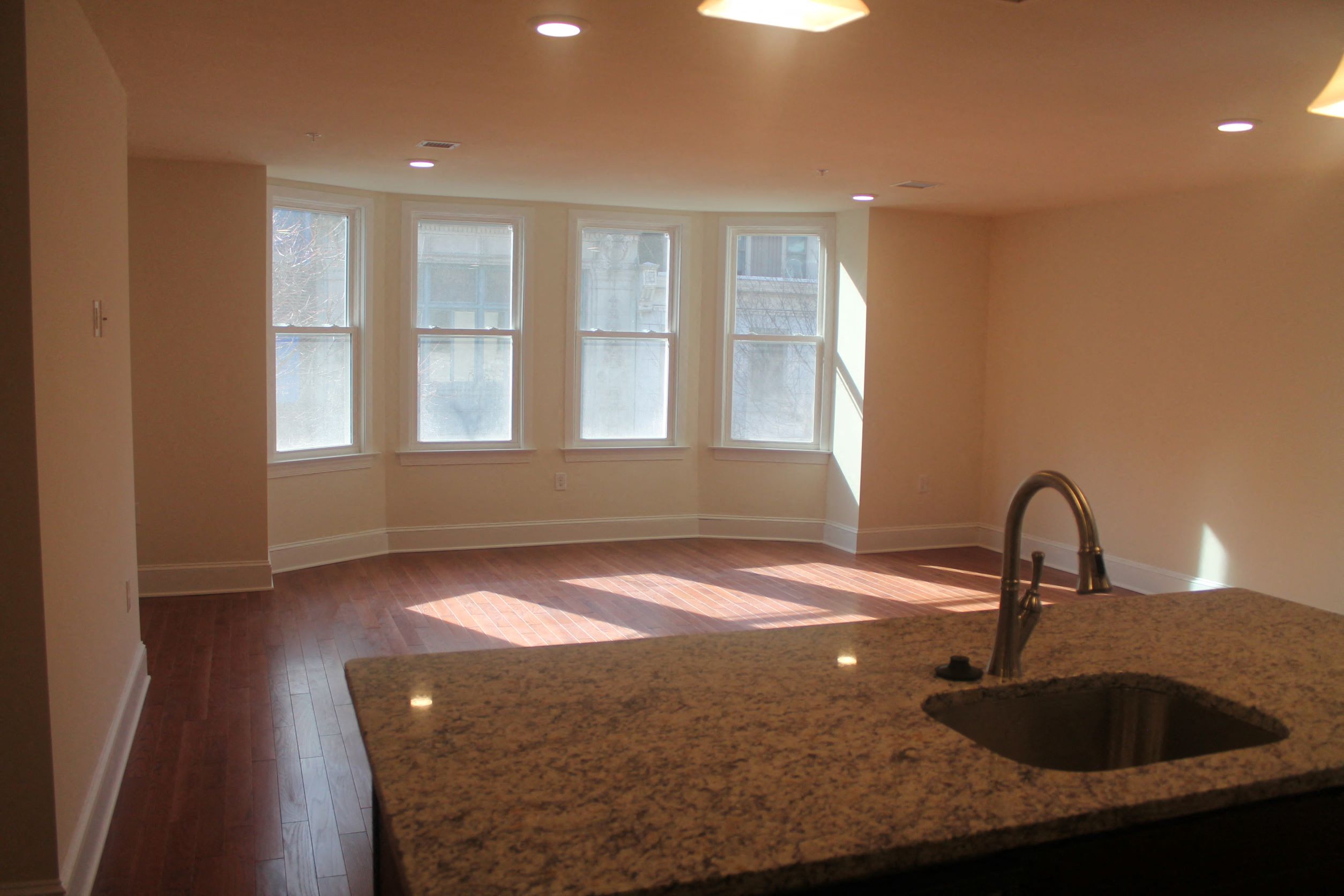 an empty living room with a sink and windows