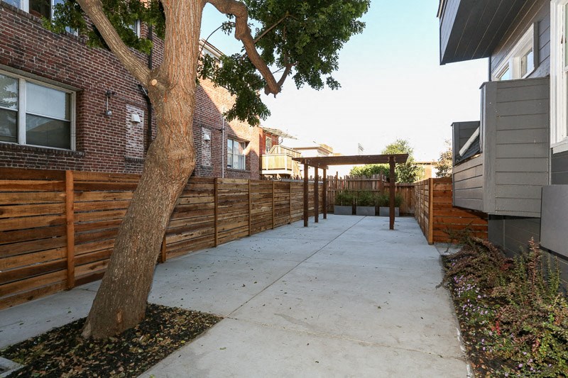 a yard with a sidewalk and a wooden fence