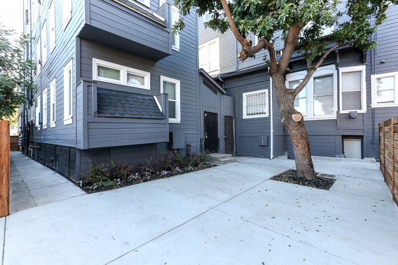 the front of a house with a sidewalk and a tree