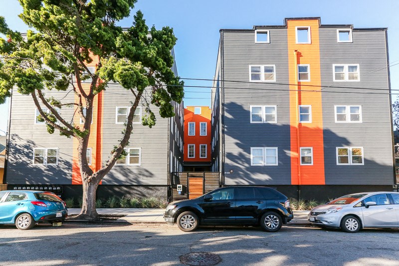 a row of apartment buildings with cars parked in front of them
