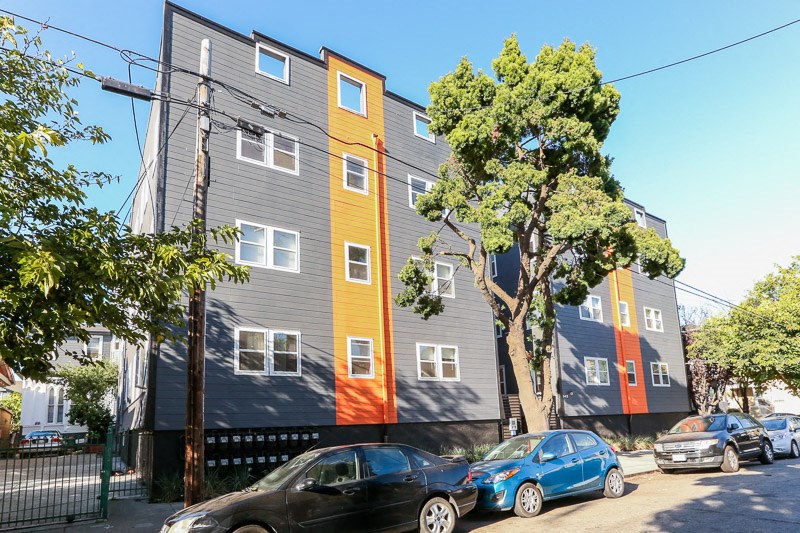 a building with different colors painted on it and cars parked in front of it