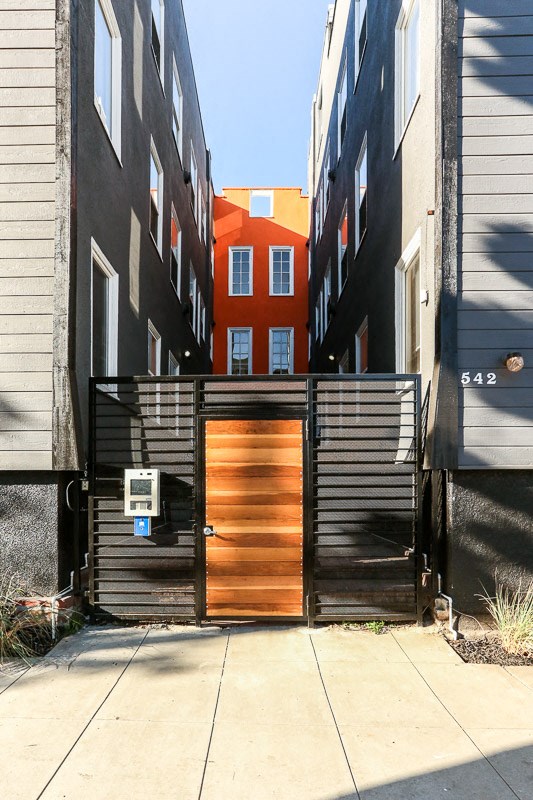 a gate with a wooden door in front of a building