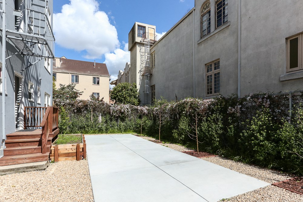 a patio with a bench and a sidewalk between two buildings
