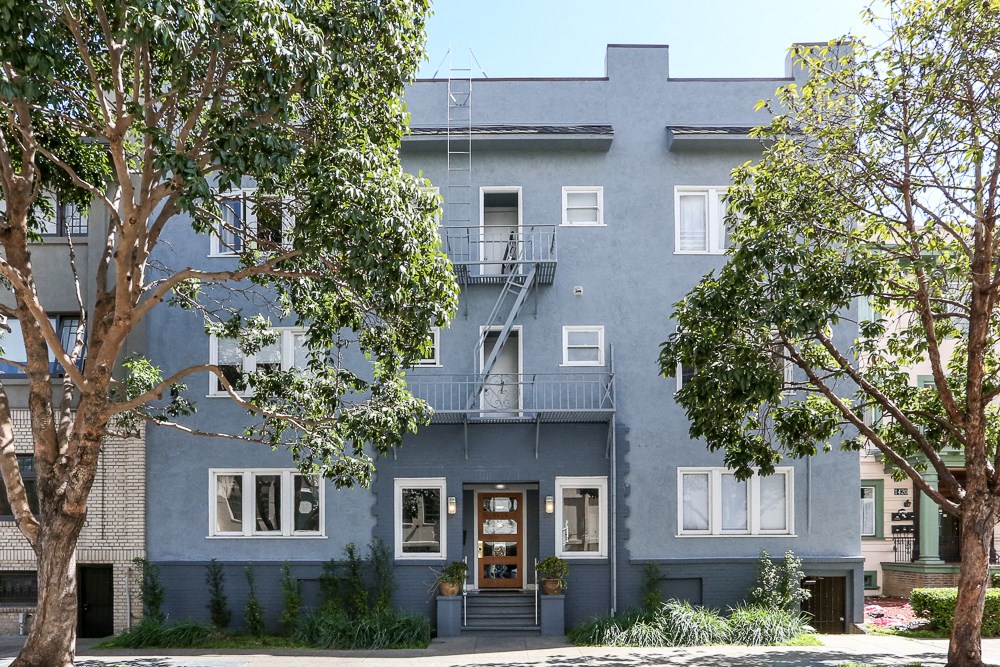 the exterior of a blue building with trees