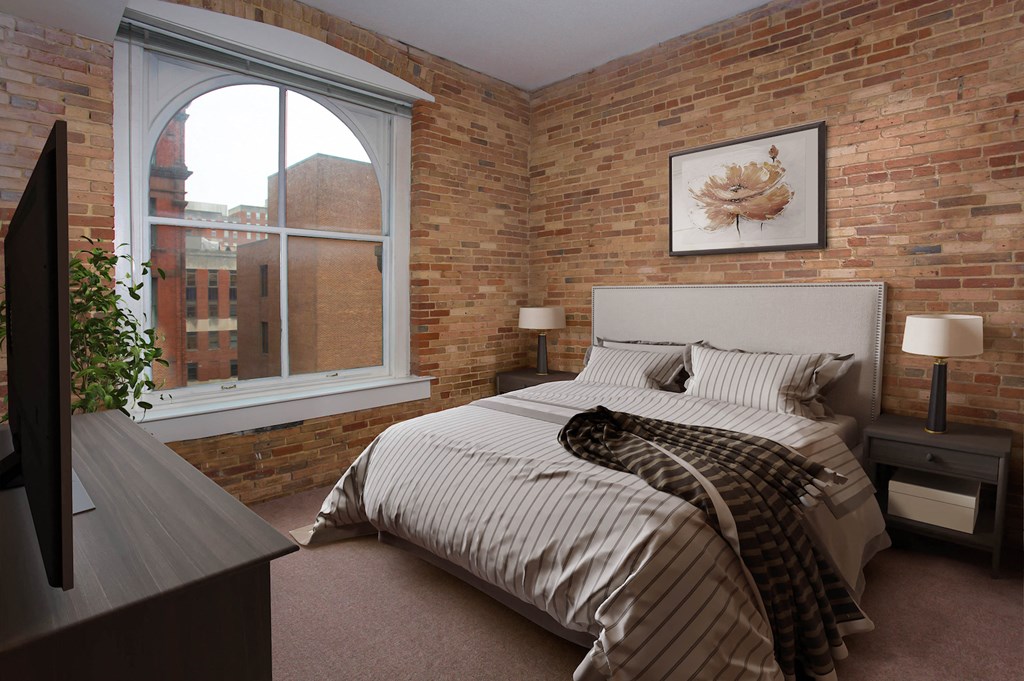 a bedroom with a bed and a brick wall