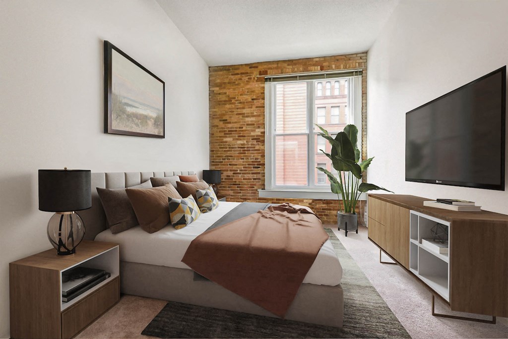 a bedroom with a bed and a tv in front of a brick wall