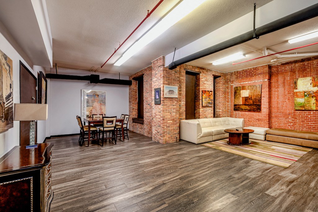 a living room and dining room with brick walls and wood floors