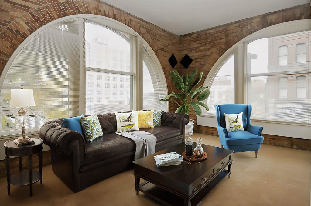 a living room with large arched windows and a brown couch