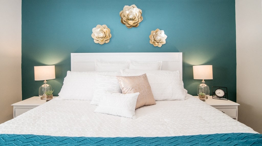 a blue and white bedroom with a white bed and flowers on the wall