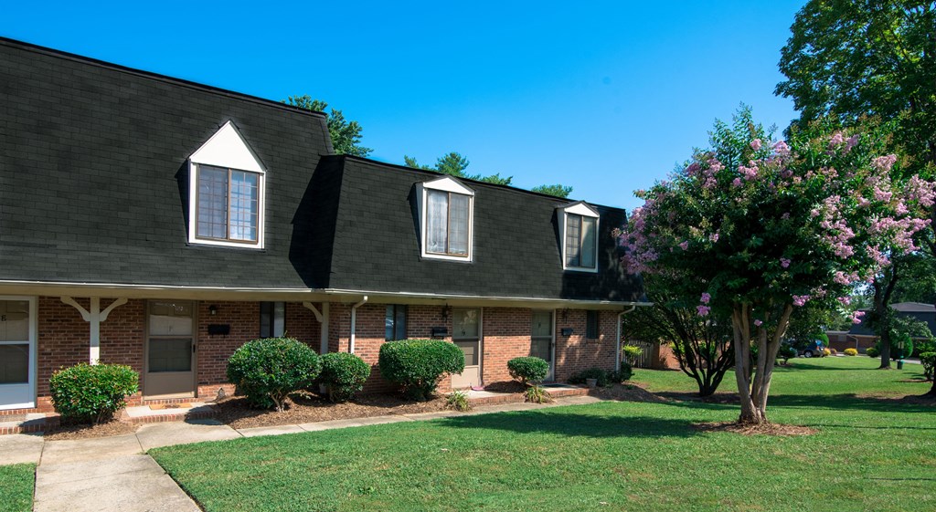 a house with a lawn and trees in front of it