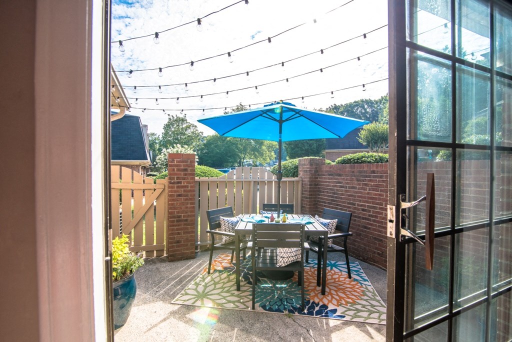 a patio with a table and chairs under a blue umbrella