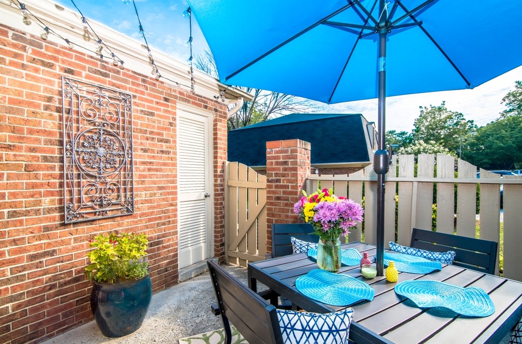 a backyard patio with a table and chairs under an umbrella