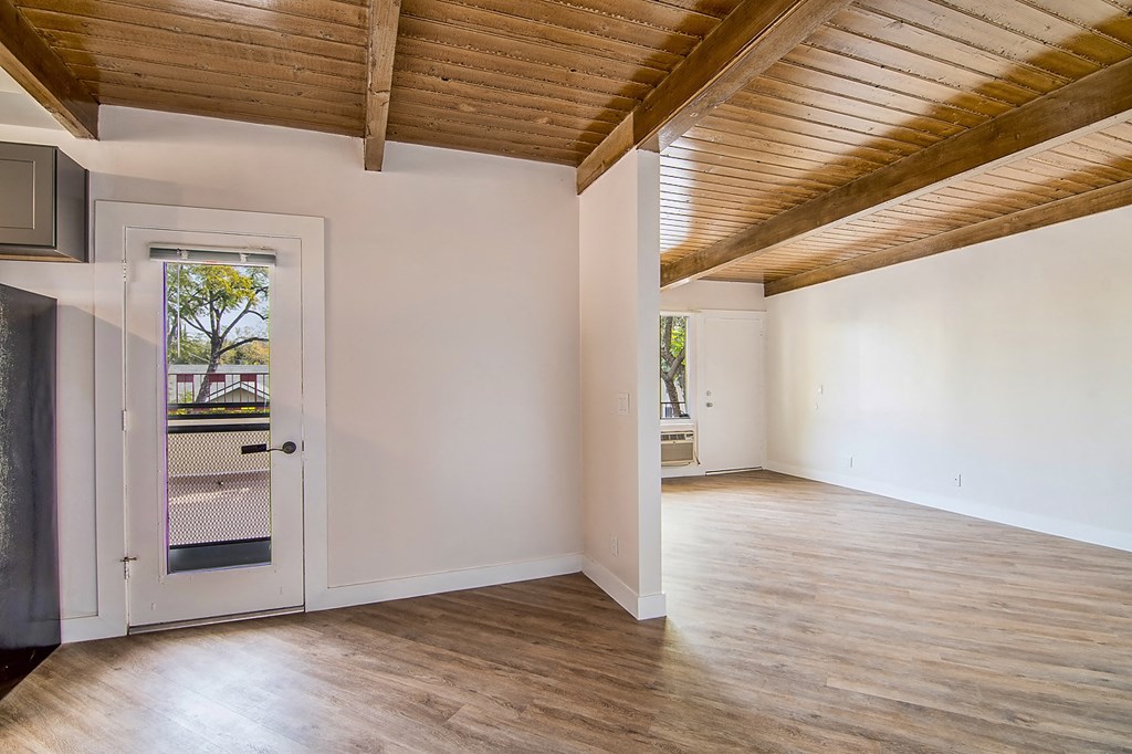 an empty living room with white walls and a door to a balcony