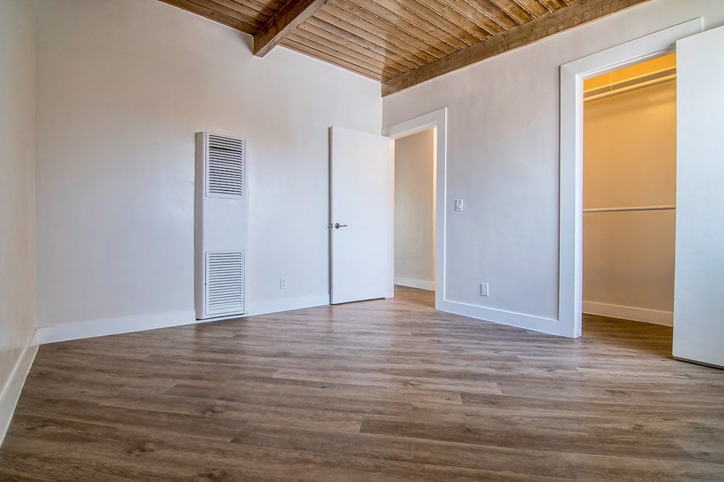 a living room with white walls and wood floors and an air conditioner