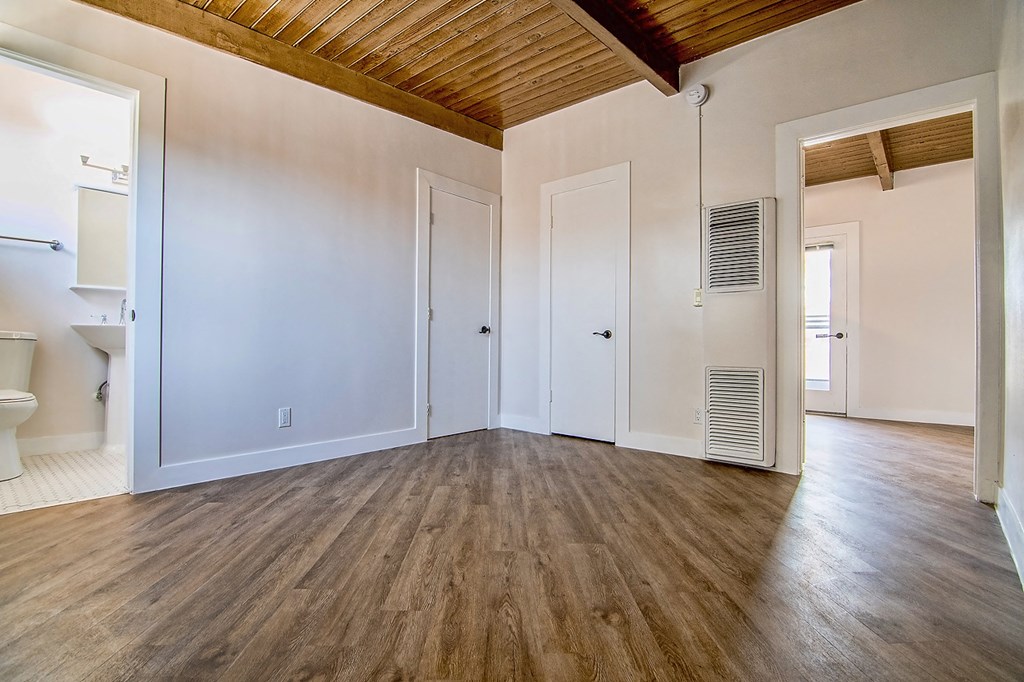 an empty living room with wood floors and white walls