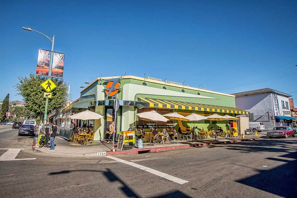 a green building with a yellow and white striped awning on a city street