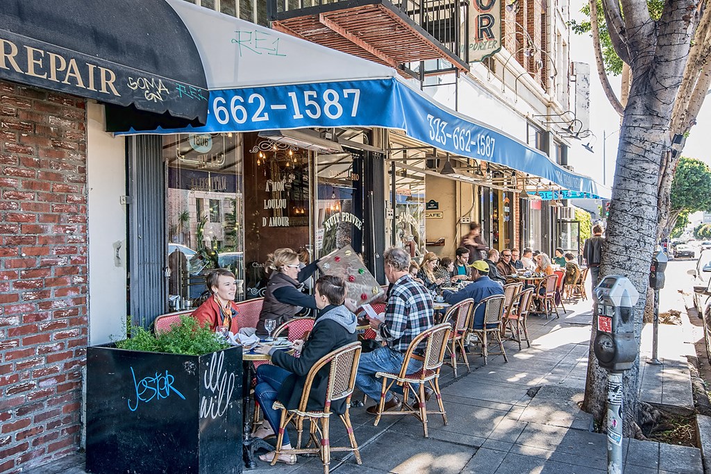 a group of people sitting at tables outside a restaurant