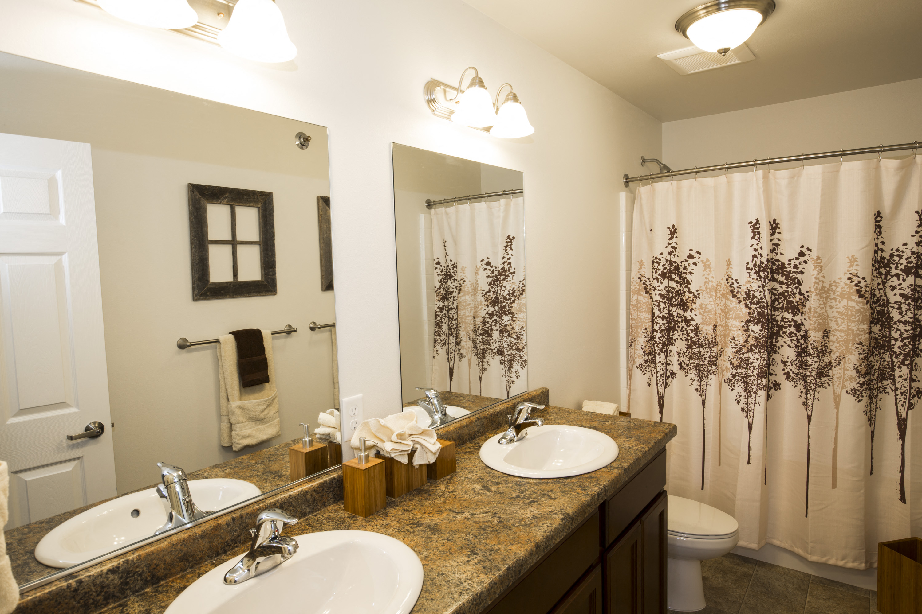Image of two sinks, toilet, two mirrors and bathtub