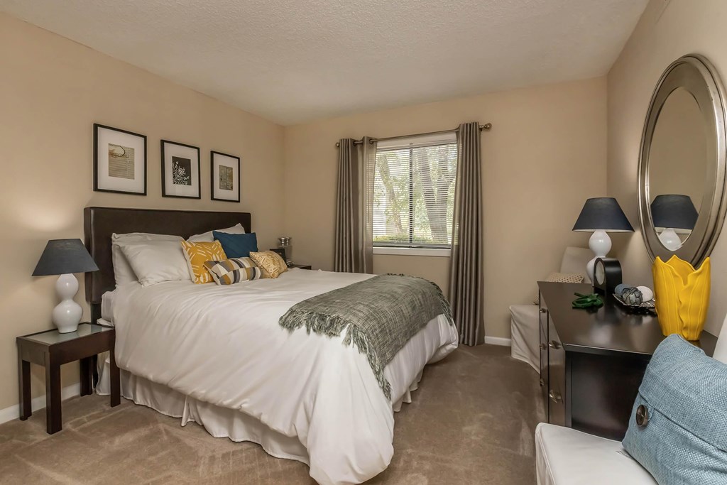 A bedroom with a large bed and a mirror on the wall.