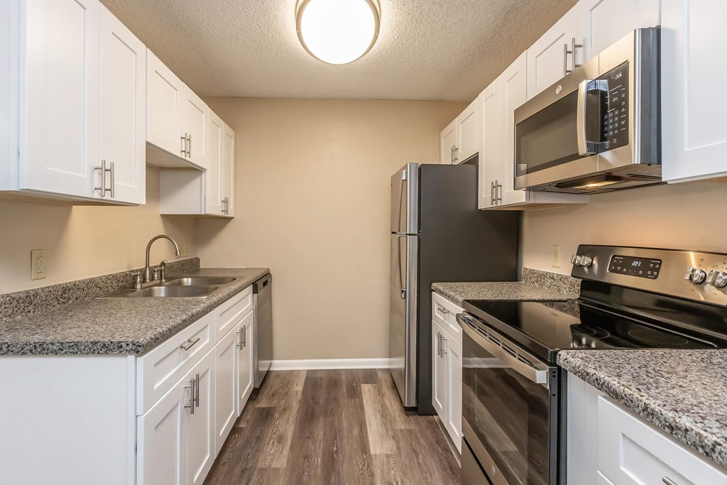A kitchen with white cabinets and a black refrigerator.