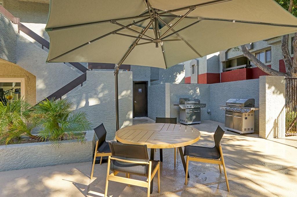 a patio with a table and chairs under an umbrella