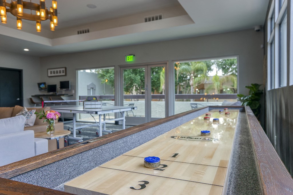 a shuffleboard table in the center of a room with tables and windows