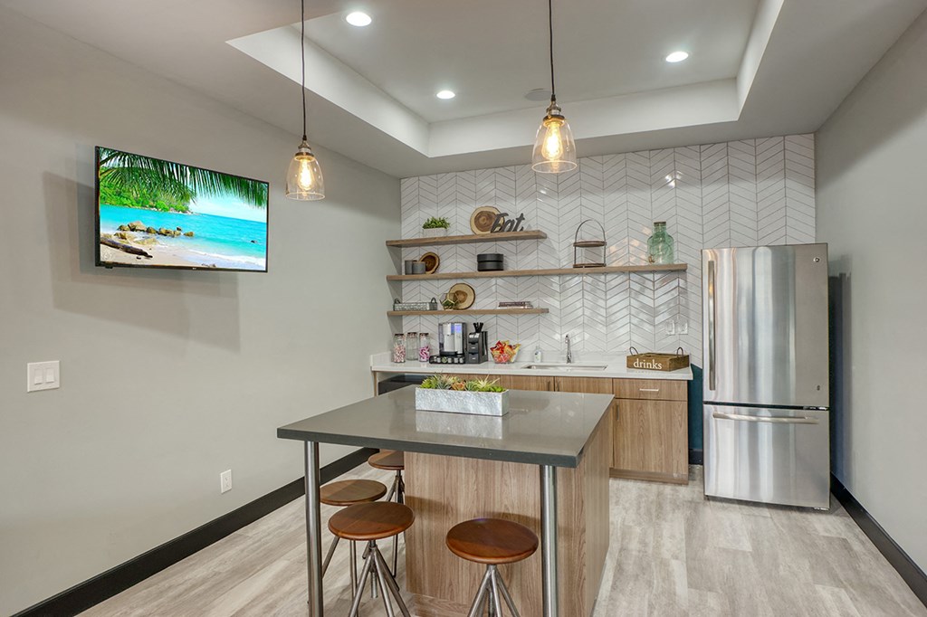 a kitchen with a island with stools and a refrigerator