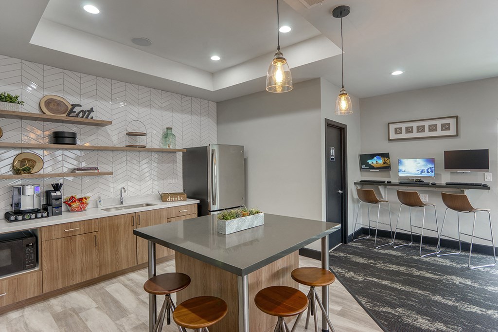 a kitchen with a counter and stools and a refrigerator