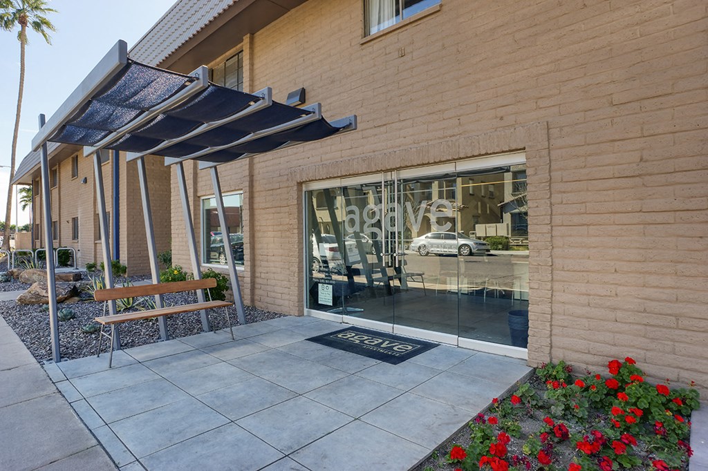 the sidewalk outside of a building with a bench and a glass door