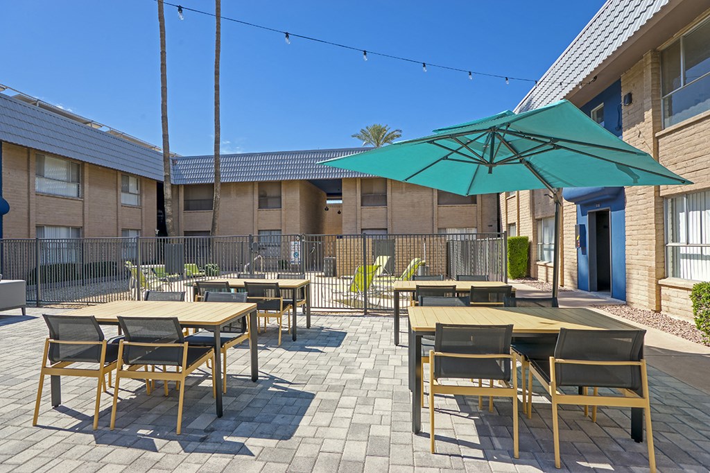 our patio is set up with tables and chairs and an umbrella