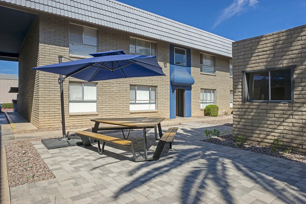 a picnic table with an umbrella outside of a building
