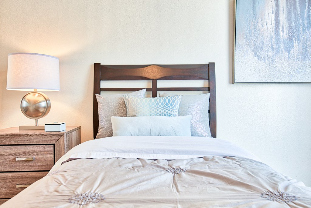 a bedroom with a bed and a nightstand with a lamp