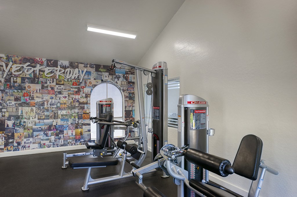 a gym with exercise machines and a wall covered in graffiti