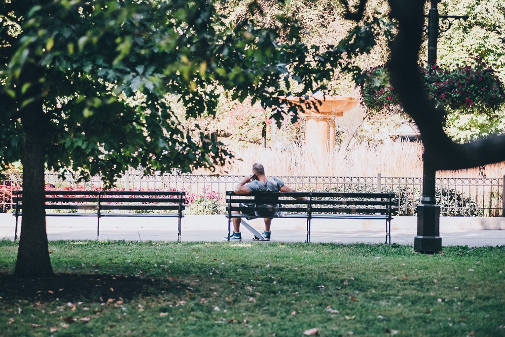 a man sitting on a bench in a park
