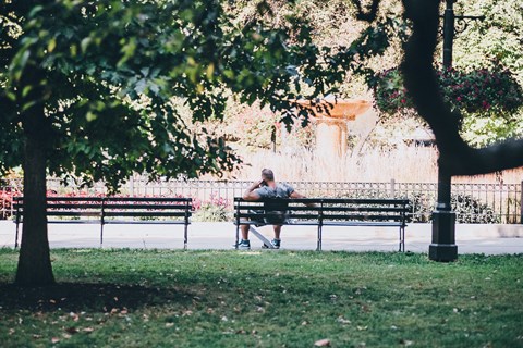 a man sitting on a bench in a park